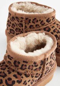 Stivaletti alla caviglia con stampa leopardata marrone, foderati in pelliccia sintetica, tessuto testurizzato e suole robuste. Presentano cuciture decorative e bordi morbidi e soffici.