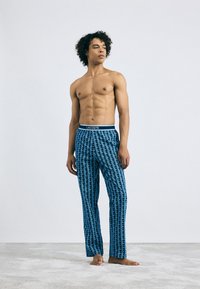 Blauwe gestreepte pyjamabroek met een zachte textuur, voorzien van een elastische tailleband met Lacoste-logo en geometrische designs overal.