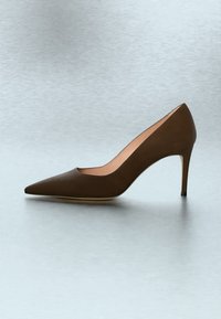 Brauner Leder-Pumps mit spitz zulaufender Zehenpartie und schlankem Stilettoabsatz auf hellgrauem Hintergrund.
