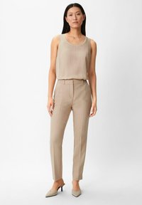 Beżowa, bezrękawnikowa bluzka w połączeniu z dopasowanymi, wysokim talii beżowymi spodniami. Strój charakteryzuje się eleganckim krojem i gładką fakturą.