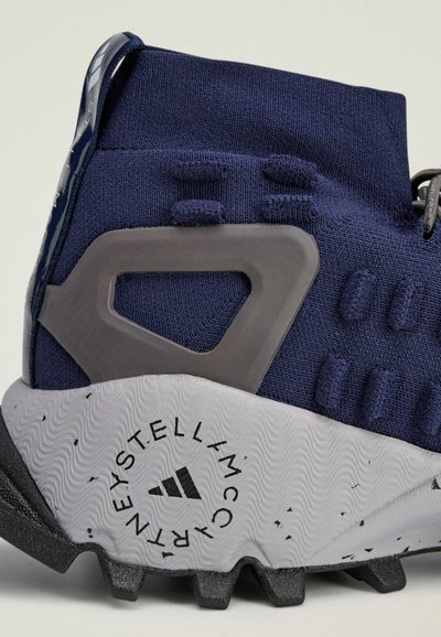 Scarpa sportiva blu navy con tomaia in tessuto testurizzato, suola in gomma grigia con battistrada distintivo e contrafforte sul tallone per supporto.
