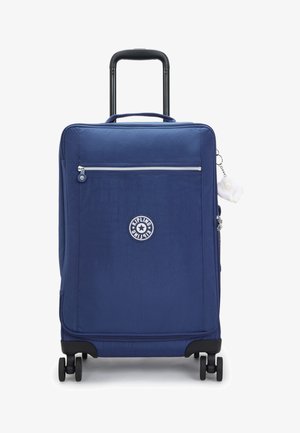 Navy blue rolling suitcase with a zippered front pocket, logo patch, and a fluffy charm attached. Features four wheels and a retractable handle.