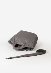 Graue, weiche Ledertasche mit integrierten Griffen und einem separaten, verstellbaren Schultergurt mit Metallverschluss auf weißem Hintergrund.