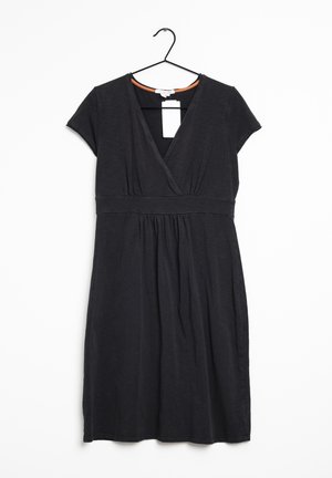 Černé šaty krátké na rukávy a ke kolenům, s výstřihem do V, pasovým pásem a nabíranou sukní, zavěšené na černém ramínku na bílém pozadí.