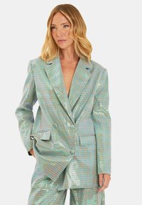Blazer a quadri iridescenti con revers a punta, design doppiopetto e tasche laterali. Il tessuto presenta una texture lucida e riflettente in tonalità pastello.