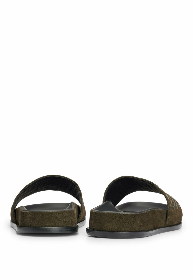 Brązowe zamszowe sandały z otwartym tyłem i szerokimi paskami, z fakturowanym wzorem, płaską czarną podeszwą i minimalistycznym designem.