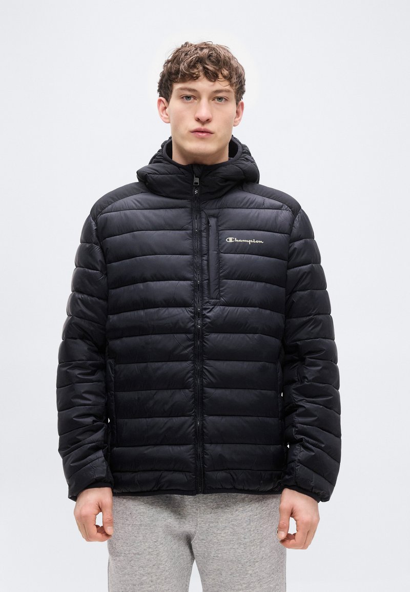 Doudoune noire avec fermeture éclair frontale et capuche. Caractérisée par un motif matelassé horizontal et un petit logo brodé sur la poitrine.