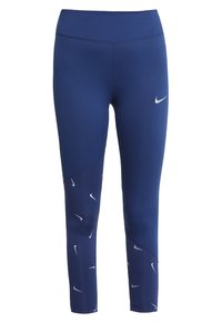 Leggings bleu marine à taille haute, en tissu extensible, avec des logos Nike blancs et un motif géométrique sur le bas de la jambe.