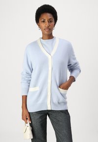 Ανοιχτό μπλε κα cardigan με κρεμ trim, που διαθέτει V-λαιμόκοψη, κουμπιά κατά μήκος μπροστά και δύο εμπρός τσέπες. Μαλακό πλεκτό υλικό.