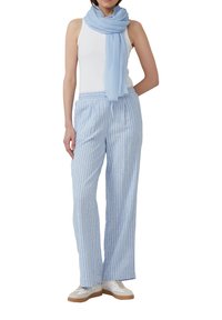 Pantalons larges bleu clair avec des rayures verticales blanches, associés à un débardeur blanc et une écharpe coordonnée bleu clair. Des baskets blanches décontractées complètent le look.