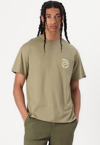 Olive green cotton t-shirt with short sleeves and a crew neck, featuring a circular white graphic text on the left chest area.