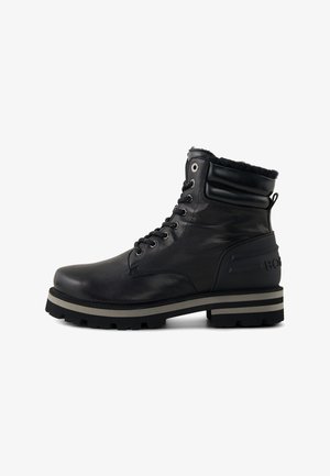 Black leather ankle boot with rubber sole, lace-up design, padded collar, and striped midsole. Features side branding and textured accents.