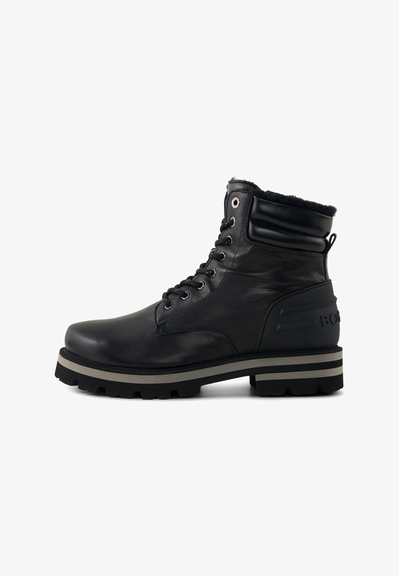 Sort læder ankelstøvle med gummisål, snørelukning, polstret krave og stribet mellemsål. Har sidestribe med mærke og teksturerede detaljer.