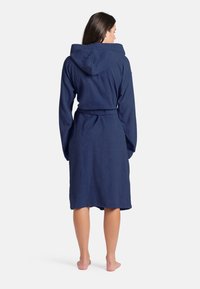 Accappatoio cappuccio blu navy realizzato in materiale texture, con cintura in vita, maniche lunghe e lunghezza fino al ginocchio.