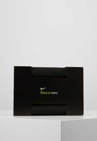 Nike Push-Up Grips mustassa laatikossa, jossa on leikattu aukko. Kahvat näyttävät sylinterimäisiltä, niissä on teksturoitu pinta, ja niissä on vihreä logo.