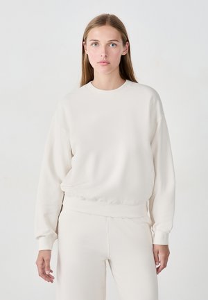 Hellbeige Pullover-Sweatshirt aus weichem Material, mit rundem Halsausschnitt, langen Ärmeln sowie gerippten Bündchen und Saum.