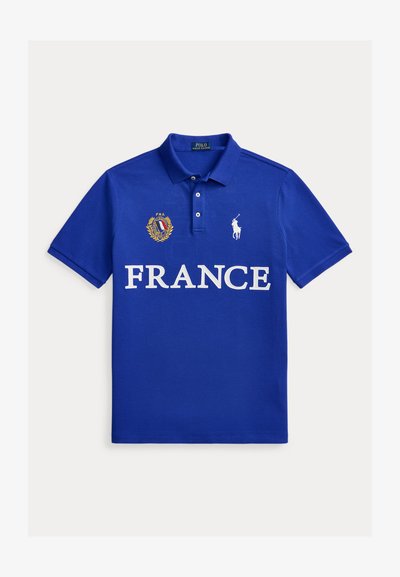 Camiseta polo azul con texto "FRANCE", emblema de Francia con bandera y laurel, y logo blanco de Polo Ralph Lauren con caballo en el pecho.