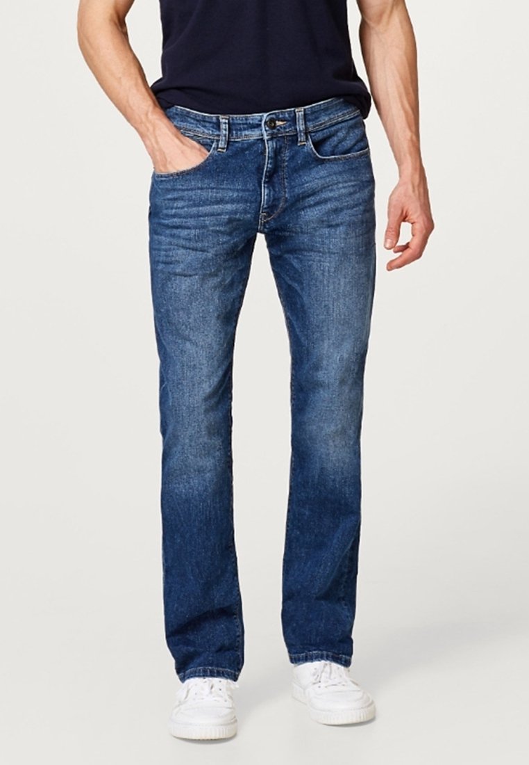 Blå denimjeans med rak passform, med knapp- och dragkedjestängning, fem fickor och en blekt tvätt effekt. Bärs med vita sneakers.