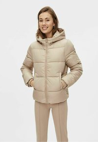 Beige dunjakke med hette, med glidelås foran, quiltet design og sidelommer. Myk tekstur og elastiske mansjetter.