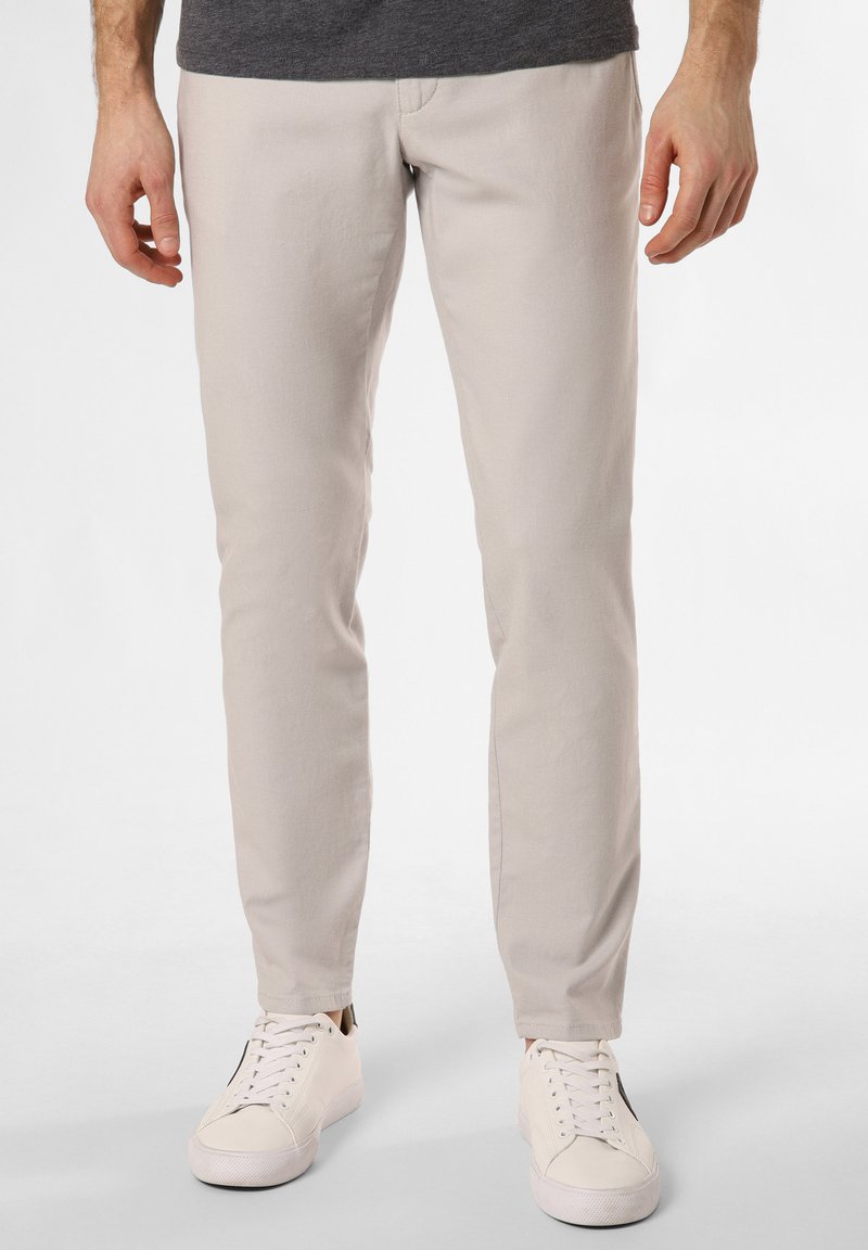 Light beige slim-fit pants made of soft fabric, featuring a simple design, straight legs, and worn with white sneakers.