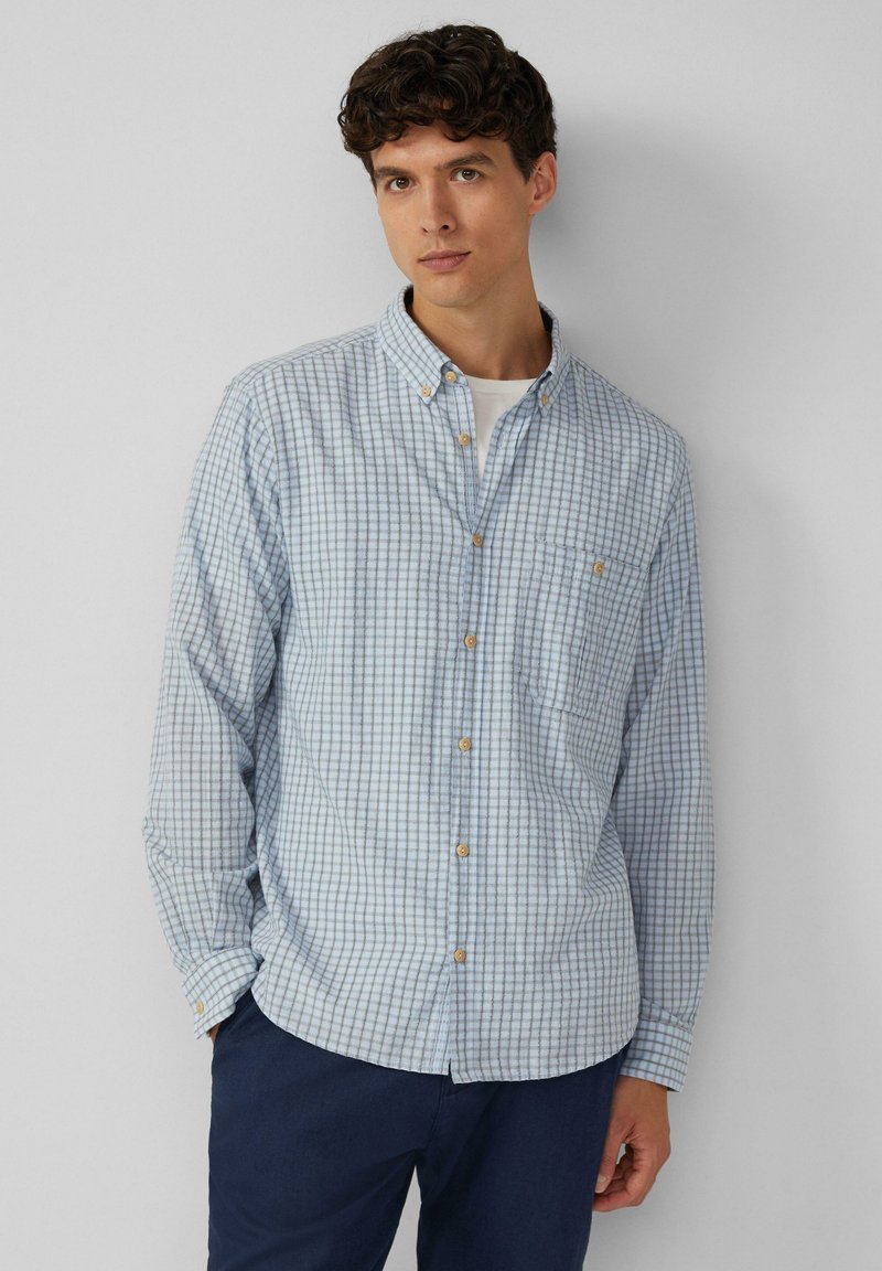 Lichtblauw geruit overhemd met button-down kraag, lange mouwen en een borstzak. Voorzien van houten knopen en een subtiel ruitpatroon.