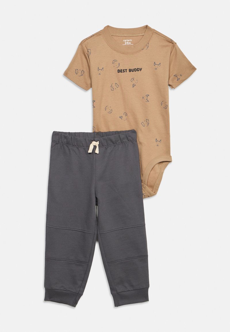 Body bébé à manches courtes de couleur tan avec le texte "BEST BUDDY" et des impressions de visage de chien, accompagné d'un pantalon gris foncé à taille élastique avec cordon de serrage.
