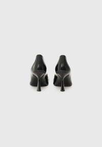 Eleganti scarpe nere in vernice con tacco alto e punta affilata, caratterizzate da un sottile tacco a stiletto e una finitura liscia e lucida.