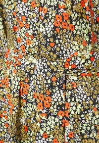 Tissu noir avec un motif floral coloré comprenant des coquelicots rouges, des fleurs blanches et des accents verts. Comprend des plis et une ceinture assortie.