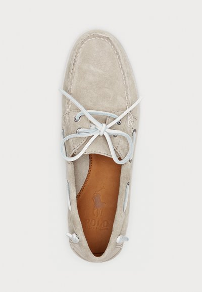Suede boat shoe in light gray with white laces. Features a stitched toe and leather insole with embossed logo. Round shape with eyelet accents.