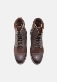 Botas de tobillo de cuero marrón y gamuza con punta redondeada, cordones en el frente y cremalleras laterales para un fácil uso. Los detalles texturizados realzan el diseño.