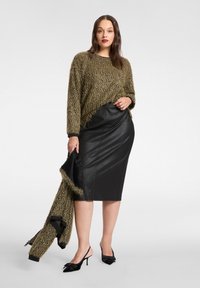 Sweter z oliwkowozielonego, teksturowanego dzianiny z postrzępionym dołem, zestawiony z czarną skórzaną ołówkową spódnicą oraz czarnymi sandałkami na obcasie ze wstążkowymi zdobieniami.