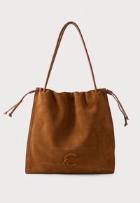 Sac fourre-tout en daim marron avec une texture douce, une bandoulière unique et des détails à cordon de serrage des deux côtés, embossé d'un petit logo près du bas au centre.