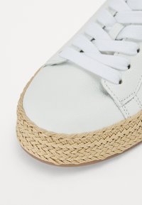 Sneaker in pelle bianca con lacci bianchi e soletta centrale in juta intrecciata naturale, caratterizzato da una punta arrotondata e superficie testurizzata.