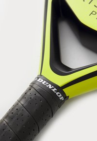 Helle gelbe Paddel mit schwarzem Rahmen, ausgestattet mit einem perforierten schwarzen Griff und dem "DUNLOP"-Logo am Griff. Glatte Oberfläche, gewinkeltes Design.