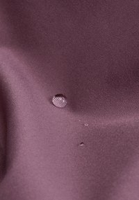 Wasserabweisender Stoff in einem sanften lila Farbton, mit einer glatten Textur und einem Wassertropfen, der auf seiner Oberfläche ruht.