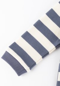 Gestreiftes Langarmkleidungsstück in Marineblau und Creme. Weicher Stoff mit gerippten Ärmelabschlüssen. Besitzt horizontale Streifen über dem Ärmel.