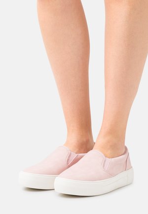 Sapatos de slip-on cor-de-rosa com uma textura de camurça suave, sola de borracha branca e detalhes elásticos laterais projetados para fácil calçar.