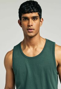 Grøn bomulds tanktop med rund halsudskæring, ærmeløs design og glat tekstur. Den tætsiddende form øger komforten og mobiliteten.