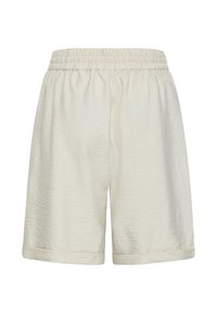 Short ample de couleur crème avec ceinture élastique et texture subtile, longueur au genou avec ourlet reversé.