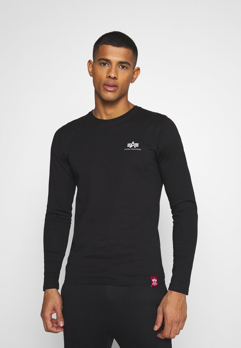 Langarm-T-Shirt in Schwarz aus weichem Baumwollstoff, mit einem kleinen weißen Logo auf der Brust und einem roten Stoffetikett am Saum.