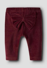 Bordeaux velours broek met een elastische tailleband. De achterkant heeft een groot, textuurdetail in de vorm van een strik, een gladde textuur en taps toelopende broekspijpen.