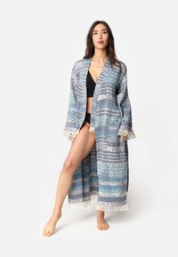 Dolgi kimono-slog odprti plašč v teksturiranih modrih in sivih vzorcih, z resastim robom in odprtim sprednjim delom, izdelan iz lahkotnega materiala.