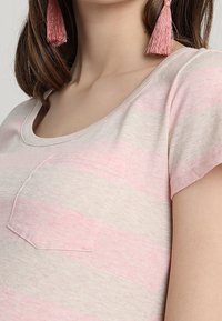 Ljusgrå t-shirt med horisontella rosa ränder, korta ärmar och en ficka på vänstra bröstet. Mjuk textur med en avslappnad passform.