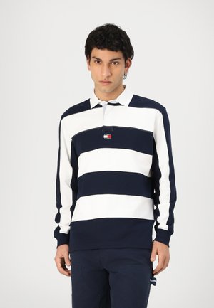 Polo shirt à rayures bleu marine et blanches à manches longues avec col et un petit logo brodé sur la poitrine. Poignets et ourlet côtelés.