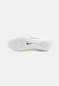 Nike-kengän pohja valkoisena ja keltaisena, jossa on teksturoitu kuosi, jossa on ympyrä- ja soikeamuotoisia aukkoja, sekä musta logoakentti.