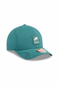 Teal baseball cap with curved brim, textile material, large logo patch featuring a bird and "Philadelphia Eagles," textured panel accents.