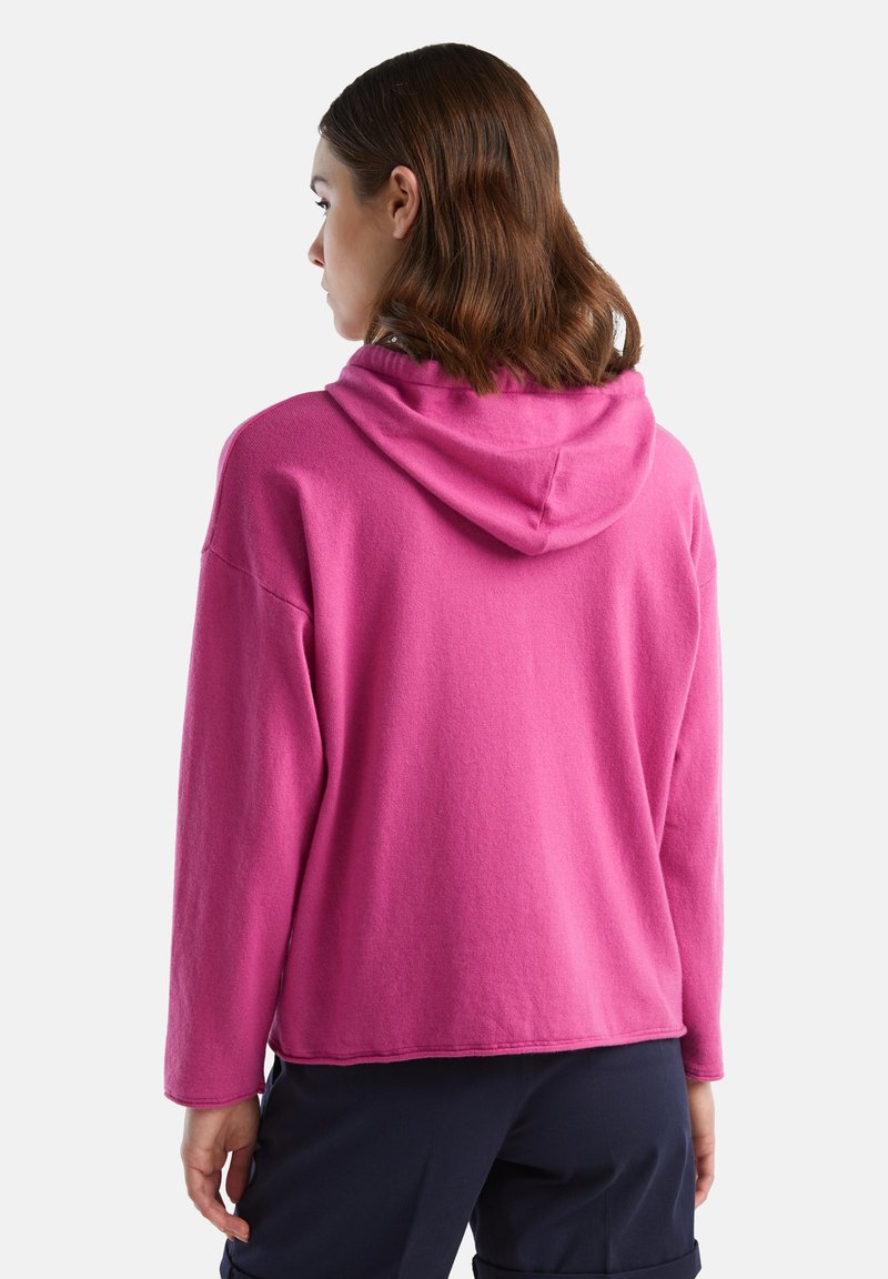 Hoodie w jaskrawym różowym kolorze, wykonany z miękkiego materiału. Posiada luźny krój, opuszczone ramiona oraz gładką strukturę z prostym wzorem.