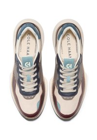 Beiga och marinblå sneakers med mesh- och läderdetaljer. Har perforerade sektioner och en lätt sula. Snören är ljusgrå.