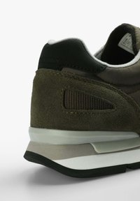 Braune Wildlederschuhe mit einer Ferse aus schwarzem Leder, einem strukturierten Mesh-Panel und einer gestuften Sohle in verschiedenen Grautönen und Weiß.