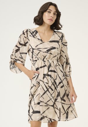 Robe avec un décolleté en V, des manches trois-quarts et un motif abstrait noir et beige. Comprend des plis doux et des poches sur les côtés.